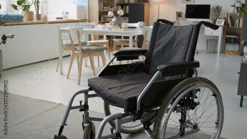 Close up shot of wheelchair standing empty in retirement home common room, representing accessibility and senior care. Clip for medical equipment ads or nursing home promotional videos
