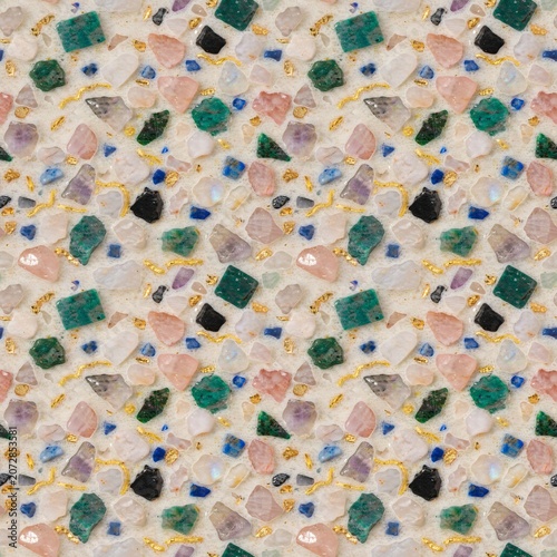 Terrazzo style surface pattern composed of colorful crushed gemstones, including quartz, amethyst, and emerald fragments with gold accents