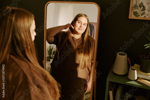 Canvastavla Young plus size Caucasian woman adjusting hair while viewing reflection in mirror, expressing body confidence and self acceptance