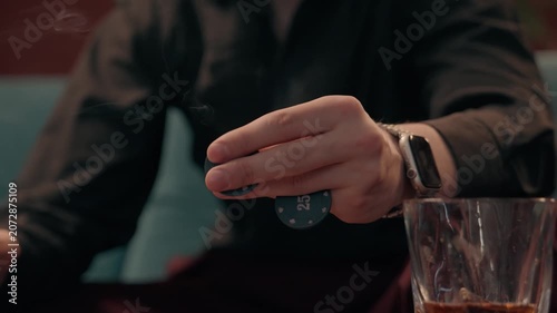 Close-up of a person holding poker chips & a cigar in a casino-style environment. Concept of gambling, betting, casino entertainment, risk taking, luxury lifestyle, gaming culture.