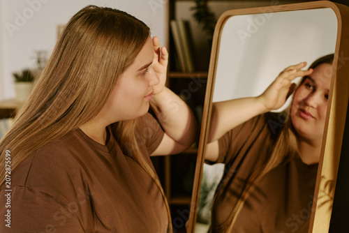 Canvastavla Caucasian young plus size woman touching forehead while looking into mirror, reflecting self image and body confidence