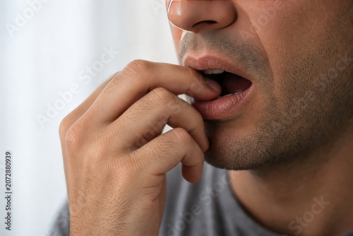 Close-up of a person biting their fingernails, showing worry or anxiety