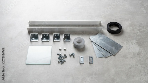 Hardware components including metal brackets and fasteners are organized on a gray surface for construction assembly.