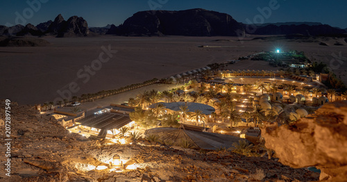 Evening view to one of modern camps in Wadi Rum, illuminated during night, vast rocky desert in distance