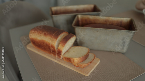 Photos Artisan sourdough bread sliced on wooden board next to metal baking tin landscap