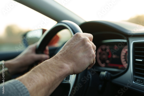Foto Male hands holding steering wheel while driving