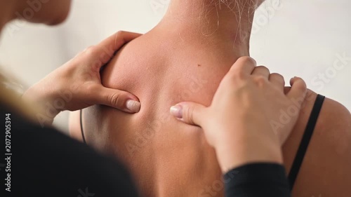 A female osteopath performs manual therapy on a female patient, focusing on the back and shoulder areas. The procedure involves hands-on techniques aimed at improving body function and overall health