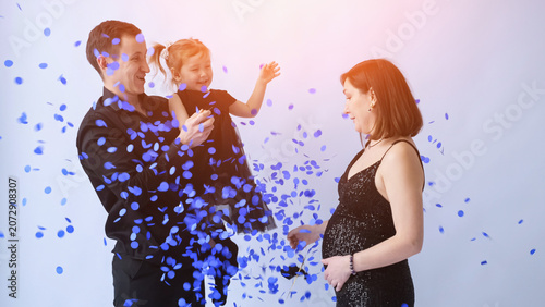 Fotografie Expecting parents and their young daughter joyfully celebrating a gender reveal