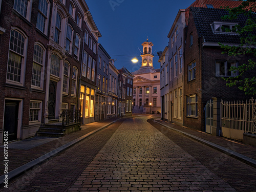 Cuadro en lienzo Dordrecht, South Holland, Holland A lively European square at dusk, featuring historic buildings with glowing windows, street lamps, and outdoor cafes