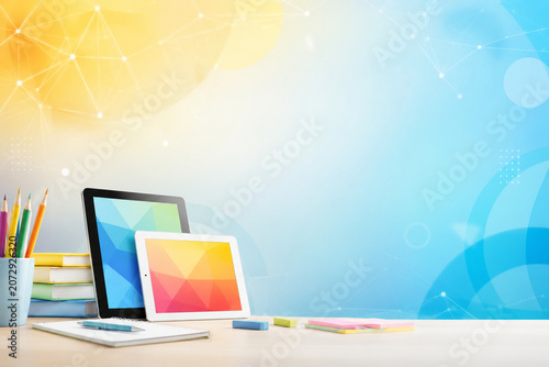 Modern workspace with digital devices and colorful stationery on a bright abstract background.