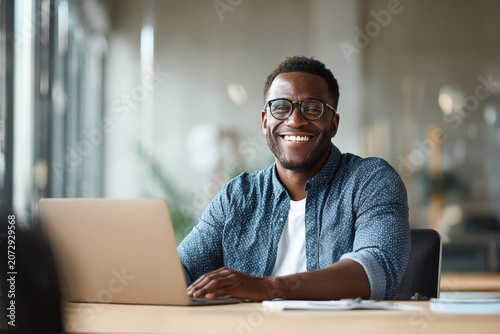 Candid head-and-shoulders portrait of a happy blogger in a contemporary workspace