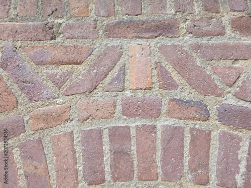 Bild auf Leinwand Close-up of red brick paving pattern with pale mortar, showing decorative geometric street texture and traditional urban detail