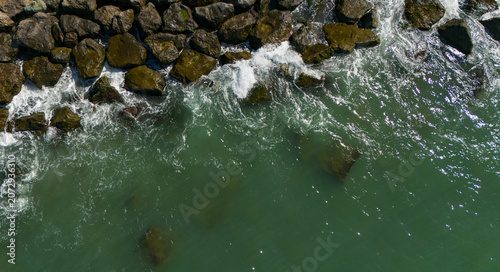 Foto Top down aerial drone view of ocean waves gently crashing against a rocky coasta