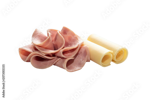 A single slice of deli ham folded into a rose shape next to two rolled slices of yellow cheddar cheese isolated on a black background