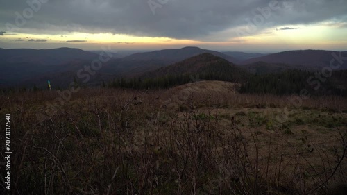 Watching the sunset from a mountain overlook in the evening with trees framing the view. Gorgany Range. Autumn hiking in Carpathian Mountains, Ukraine
