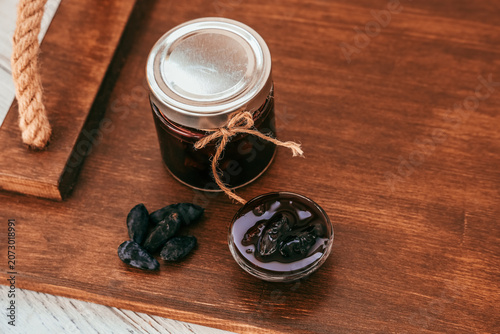 Tableau sur toile Blue honeysuckle jam in a jar with a small dish on a wooden surface with berries