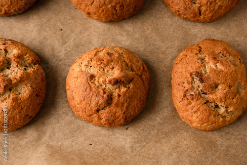 A top-down view shows golden-brown oatmeal cookies with cracked, rustic surfaces arranged neatly on parchment paper, evoking a warm, homemade feel.