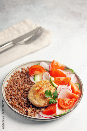 Fotografía Chicken cutlet with buckwheat porridge and vegetable salad in a plate on the table