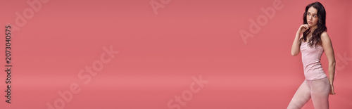 Quadro su tela Charming young woman in soft pastel attire poses gracefully against a vibrant ba