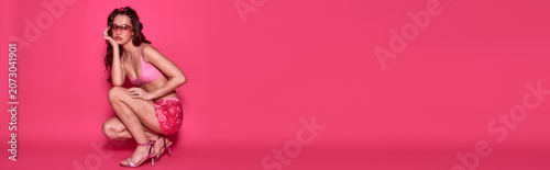 Foto Young woman showcases summer fashion in vibrant swimwear against a pink backdrop