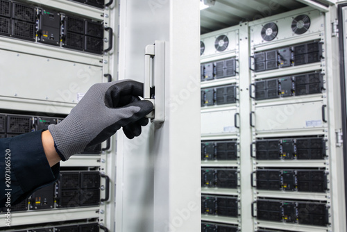 Canvastavla Technician wearing gloves opens a server rack door in a data center
