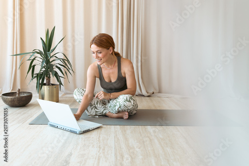Woman doing online yoga workout using laptop at home