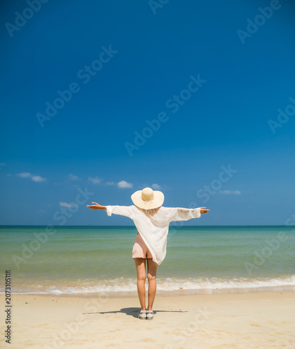 Happy woman with outstretched arms enjoying summer vacation on tropical beach, symbolizing freedom, wellness, work-life balance for corporate travel and health insurance campaigns.