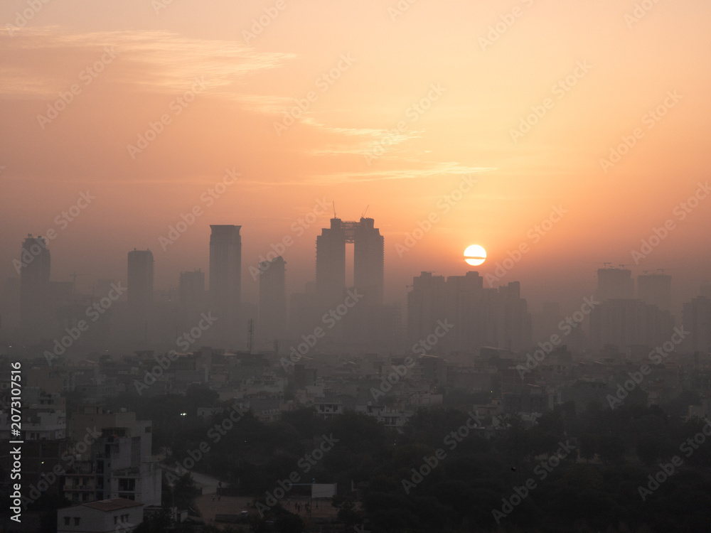 Fototapeta premium Aerial drone shot sunrise high rise skyscraper buildings at hidden in smog showing the cityscape of Gurgaon Delhi India