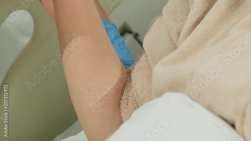 Nurse presses cotton pad on woman arm after catheter removal in bed. Woman keeps arm bent while medical worker stops bleeding at puncture site