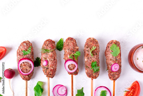 Mutton Lula Kebab on skewers in a row on white table. Caucasian cuisine meal. Top view. Copy space