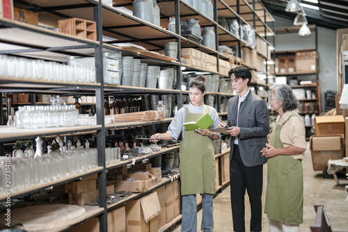 Photos Senior female entrepreneur walks the homeware stockroom aisle reading a clipboar