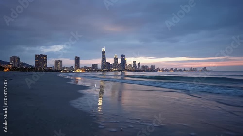 Coastal city skyline at twilight from a sandy beach