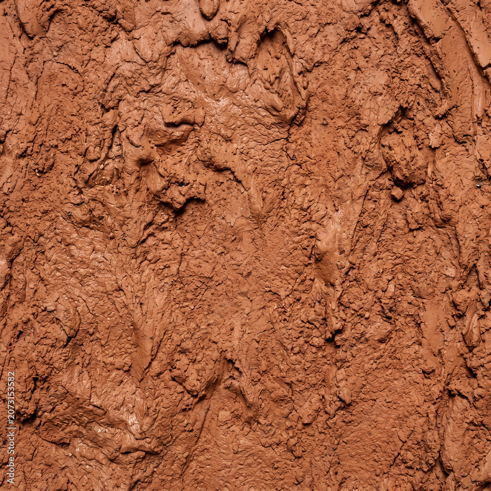 Fototapeta premium Closeup of rough textured red clay surface showcasing natural earthy tones and uneven patterns