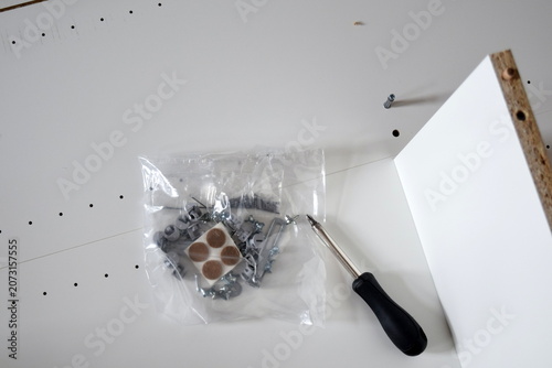 Unassembled white wooden furniture parts screws and hand tool closeup diy home renovation concept	 