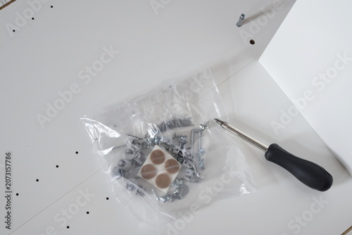 Unassembled white wooden furniture parts screws and hand tool closeup diy home renovation concept	 