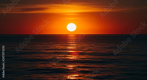 Beautiful bright orange sun setting into the dark blue ocean horizon