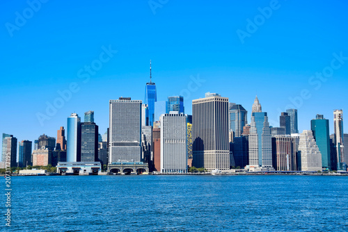 Brooklyn Bridge spanning East River with DUMBO waterfront buildings and Welcome sign visible on clear sunny day, New York City, USA