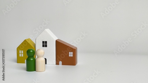 Tableau sur toile Real estate investment and family home concept with a wooden peg doll couple standing next to miniature houses with copy space