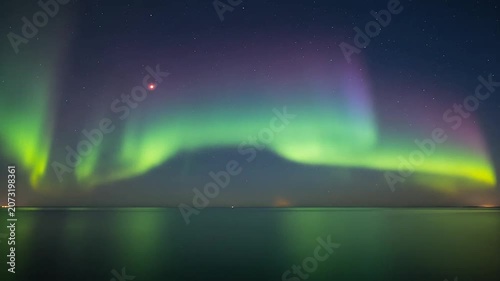 Vibrant northern lights glowing over coastal horizon.