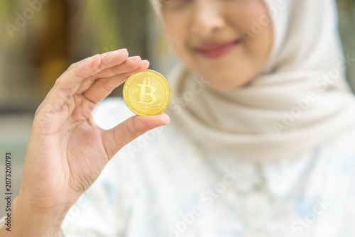 Young Asian muslim Businessman woman Holding Bitcoin. Digital Money and Bitcoin Concept.