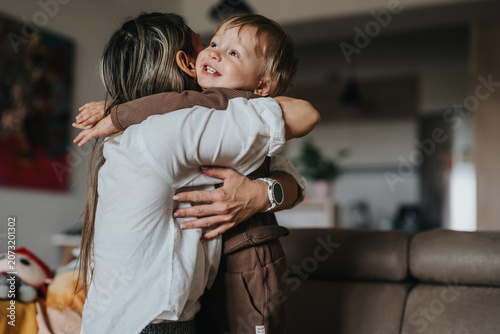 Foto Mother hugging her toddler son in a cozy living room