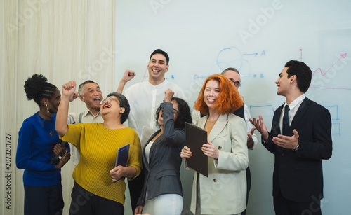 Fotografie Multi-ethnic business team cheering celebrating success modern office