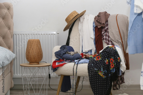 Tableau sur toile Armchair covered with clothes, used as a clothing drop zone, representing everyd