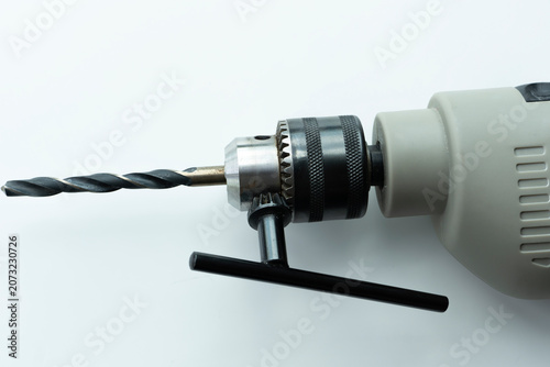 Electric drill with metal drill bit isolated on a white background. Close-up of power tool for construction, woodworking, metalworking and DIY projects with copy space.