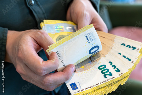 Close-up of hands counting 200 euro banknotes. Cash transaction, financial management, banking, savings and business finance concept.