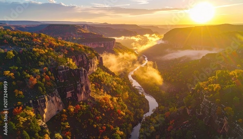 A stunning aerial view captures a winding river flowing through a canyon during a vibrant autumn sunset.