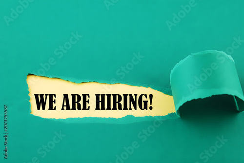 We Are Hiring Message Revealed Through Torn Turquoise Paper For Recruitment Career Opportunity And Human Resources Concept