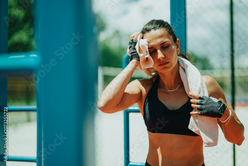 Принти на полотні Woman athlete wipes sweat with a towel after an intense outdoor workout
