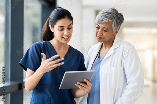 Candid moment: diverse female doctors discussing tablet data in