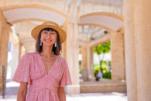 A stylish young woman stands on a street in Jerusalem and smiles. Traveling in Israel.